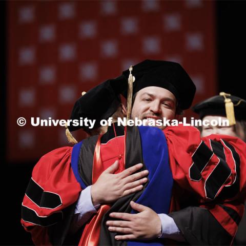 Joseph Maestas hugs his professor after being receiving his doctoral hood. Graduate Commencement. May 17, 2024. Photo by Craig Chandler / University Communication and Marketing.