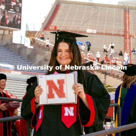 Bella Galindo, a Graphic Design and Advertising and Public Relations major, shows off her diploma. Undergraduate Commencement in Memorial Stadium. May 18, 2024. Photo by Kristen Labadie / University Communication.