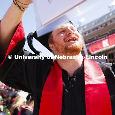 Keaton Worley waves to family and friends after walking off the stage with his College of Business diploma. Undergraduate Commencement in Memorial Stadium. May 18, 2024. Photo by Craig Chandler / University Communication and Marketing.