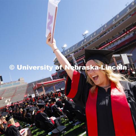 Chaylee Tonniges waves her Animal Science diploma to family and friends after walking offstage in Memorial Stadium. Undergraduate Commencement in Memorial Stadium. May 18, 2024. Photo by Craig Chandler / University Communication and Marketing.