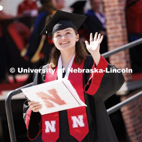 LeAnne Bugay waves to the camera as she watches herself on the HuskerVision screen in Memorial Stadium. Undergraduate Commencement in Memorial Stadium. May 18, 2024. Photo by Craig Chandler / University Communication and Marketing.
