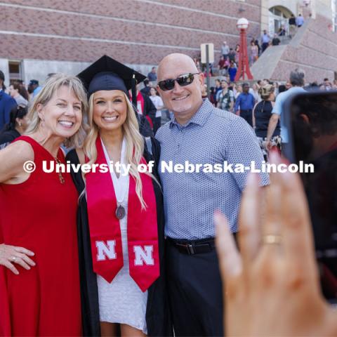 One newly gradated student poses for a picture with her parents. Undergraduate Commencement in Memorial Stadium. May 18, 2024. Photo by Craig Chandler / University Communication and Marketing.