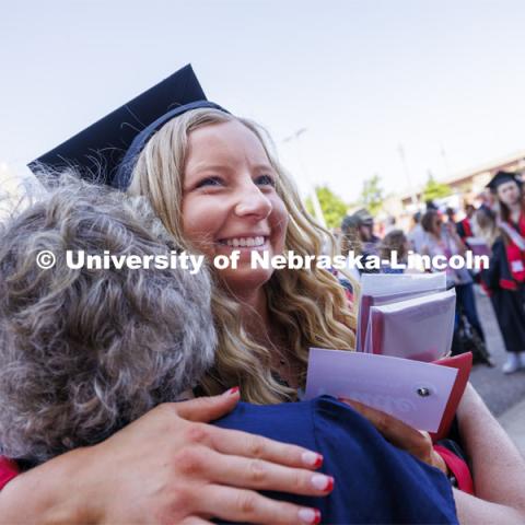 Kaitlyn Lilly is hugged by relatives after the ceremony. Undergraduate Commencement in Memorial Stadium. May 18, 2024. Photo by Craig Chandler / University Communication and Marketing.
