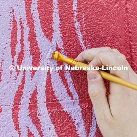 Lavender stripes are added to a flower petal on the mural. ARTS 398 - Special Topics in Studio Art III taught by Sandra Williams. The class painted a mural at the Premier Buick, Chevrolet, and GMC dealership in Beatrice. June 3, 2024. Photo by Craig Chandler / University Communication and Marketing.