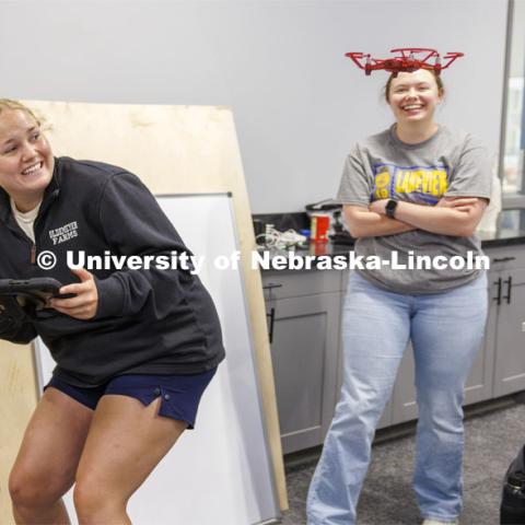 Taryn Miller, a senior in agriculture education from Amherst, Nebraska, ducks as the drone she is learning to fly comes a little close to her. In the background is her flying partner, Rebecca Wulf who just graduated in agriculture education and will teach this fall at Lakeview Community Schools near Columbus. The two are taking the class at Nebraska Innovation Studio to get their FAA license to fly UAVs. June 18, 2024. Photo by Craig Chandler / University Communication and Marketing.