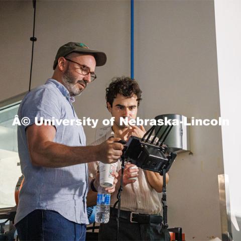 Aaron Nix and Matthew Strasburger look over camera angles while filming the Nebraska Innovation Studios welding robot. Behind the scenes photo for the university's new "Home Again" national advertisement. June 25, 2024. Photo by Kristen Labadie / University Communication.   