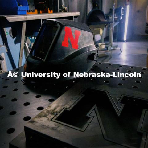 A welding helmet rests on the robotic welding table at Nebraska Innovation Studios. Behind the scenes photo for the university's new "Home Again" national advertisement. June 25, 2024. Photo by Kristen Labadie / University Communication.   