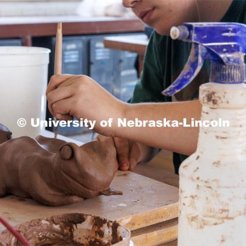 An art student molds her frog sculpture from clay. Behind the scenes photo for the university's new "Home Again" national advertisement. June 25, 2024. Photo by Kristen Labadie / University Communication.