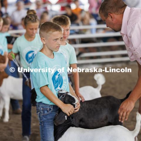 Jeter Zelasney listens to goat judge John Alfs talk about his goat in the Meat Goat Junior Showmanship competition. 4-H Polk County Fair in Osceola, Nebraska. July 19, 2024. Photo by Craig Chandler / University Communication and Marketing.