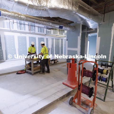 Workmen look over plans in the new women’s locker room. The raised areas will be for the lockers. Construction continues to renovate the locker rooms and a new weight training and conditioning area. Campus Recreation Center. July 30, 2024. Photo by Craig Chandler / University Communication and Marketing.