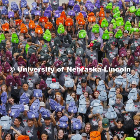 Students hold up their colored backpacks. 300 Center for Academic Success and Transition (CAST) first-year students and 48 mentors pose for a group photo at the end of their four-day camp. August 22, 2024. Photo by Craig Chandler / University Communication and Marketing.