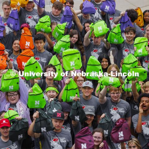 Students hold up their colored backpacks. 300 Center for Academic Success and Transition (CAST) first-year students and 48 mentors pose for a group photo at the end of their four-day camp. August 22, 2024. Photo by Craig Chandler / University Communication and Marketing.