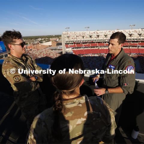 From atop the west stadium roof, Air National Guard Major Bobby Sullivan with the 175th fighter squadron of the 114th fighter wing based out of Sioux Falls, South Dakota, right, talks with Air Force ROTC cadets Mason Beck, left, and Elena Burgwald as they discuss the flyover and air force flying before the game. Nebraska vs. Illinois football game. September 20, 2024. Photo by Craig Chandler / University Communication and Marketing.