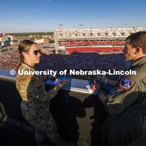 From atop the west stadium roof, Air National Guard Major Bobby Sullivan with the 175th fighter squadron of the 114th fighter wing based out of Sioux Falls, South Dakota, right, talks with Air Force ROTC cadet Elena Burgwald as they discuss the radio procedures for the flyover before the game. Nebraska vs. Illinois football game. September 20, 2024. Photo by Craig Chandler / University Communication and Marketing.