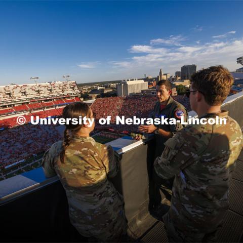 From atop the west stadium roof, Air National Guard Major Bobby Sullivan with the 175th fighter squadron of the 114th fighter wing based out of Sioux Falls, South Dakota, right, talks with Air Force ROTC cadets Mason Beck, left, and Elena Burgwald as they discuss the flyover and air force flying before the game. Nebraska vs. Illinois football game. September 20, 2024. Photo by Craig Chandler / University Communication and Marketing.