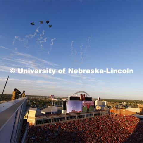 From atop the west stadium roof, Air National Guard Major Bobby Sullivan with the 175th fighter squadron of the 114th fighter wing based out of Sioux Falls, South Dakota, and Air Force ROTC cadets Mason Beck, left, and Elena Burgwald watch a successful flyover by four F-16s from the Sioux Falls, South Dakota airbase. Nebraska vs. Illinois football game. September 20, 2024. Photo by Craig Chandler / University Communication and Marketing.