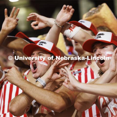 Cheering fans throwing the bones in the student section wear red and white striped overalls. Nebraska vs. Illinois football game. September 20, 2024. Photo by Craig Chandler / University Communication and Marketing.