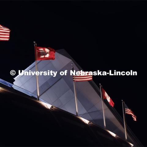 Flags on the top of Memorial Stadium are illuminated in the night sky at the Nebraska vs. Illinois football game. September 20, 2024. Photo by Craig Chandler / University Communication and Marketing