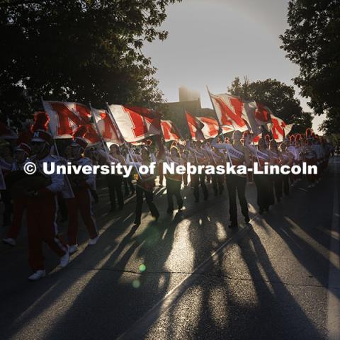 Cornhusker Marching Band color guard throws shadows along R Street as they march the parade route. Cornchella Homecoming Parade and Cornstock. October 4, 2024. Photo by Craig Chandler / University Communication and Marketing.