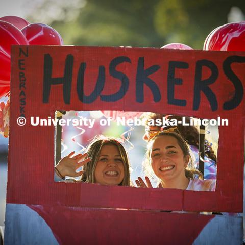 Two students ride in a Huskers float at the Cornchella Homecoming Parade and Cornstock. October 4, 2024. Photo by Craig Chandler / University Communication and Marketing.