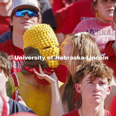 Ryan Jensen gets a kiss from his girlfriend, Emmy Oldham. Jensen a senior from Lincoln, wore his own version of a corn head knitted by Oldham of Wellfleet, Nebraska. Jensen said it felt about 20 degrees hotter inside the headgear. Nebraska vs Rutgers football game. Homecoming game. October 5, 2024. Photo by Craig Chandler / University Communication and Marketing.