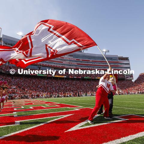 Husker Cheer Squad member Jake Seip fights the high wind speeds with Herbie Husker’s help as he tries to wave the huge N flag as the Huskers took the field. Nebraska vs Rutgers football game. Homecoming game. October 5, 2024. Photo by Craig Chandler / University Communication and Marketing.