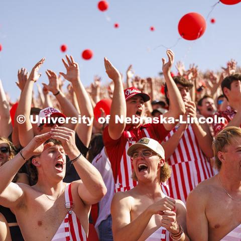 Cheering fans in the student section wear red and white striped overalls. Nebraska vs Rutgers football game. Homecoming game. October 5, 2024. Photo by Craig Chandler / University Communication and Marketing.