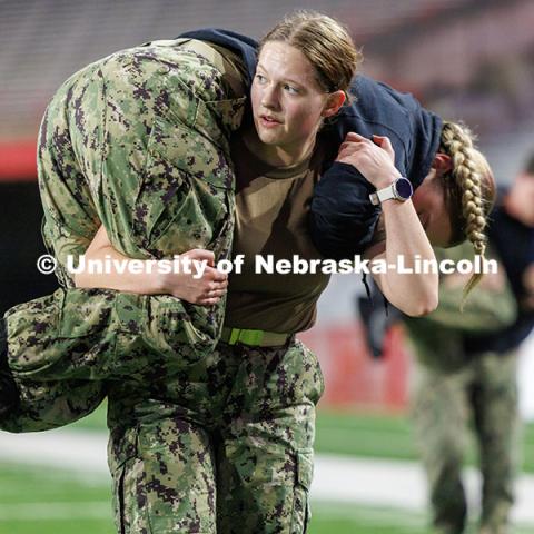 Midshipman Leah Lindhart carries a fellow NROTC member across the field. Navy and Marine Corps 249th birthday celebration physical training in Memorial Stadium. November 8, 2024. Photo by Jordan Opp / University Communication and Marketing.