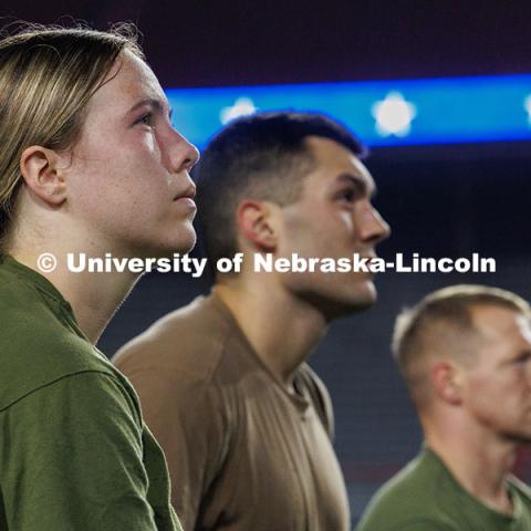 Midshipman Elianna Bryne, from left, Ensign Peyton Weigand, and Gunnery Sergeant Scott Johnson watch a video on the Huskervision screen. Navy and Marine Corps 249th birthday celebration physical training in Memorial Stadium. November 8, 2024. Photo by Jordan Opp / University Communication and Marketing.