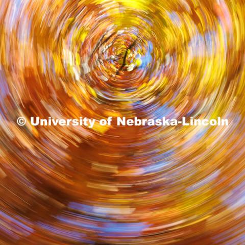 Orange, red, and yellow leaves blend into a vortex near the Nebraska Union in this photo taken at a slow shutter speed while spinning the camera in a circle. Fall on City Campus. November 12, 2024. Photo by Jordan Opp / University Communication and Marketing.