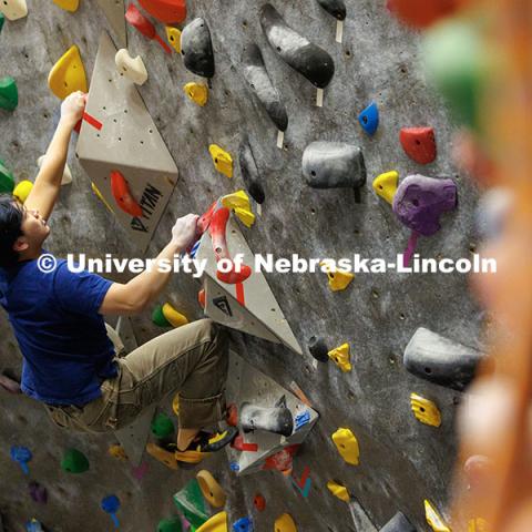 Andy Tran, freshman, climbs up the wall in the Campus Recreation facility on City Campus. The League of Extraordinary Boulderers program is designed to teach participants climbing techniques and build friendships with others interested in bouldering. November 20, 2024. Photo by Jordan Opp / University Communication and Marketing.