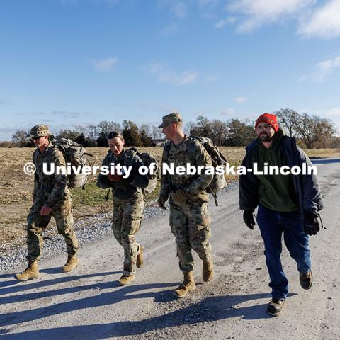 Army ROTC cadets Malorie Mulligan and Max Holmstrom (center) look at the football they are carrying from Wabash to Alvo. Ruck March. November 21, 2024. Photo by Jordan Opp / University Communication and Marketing.