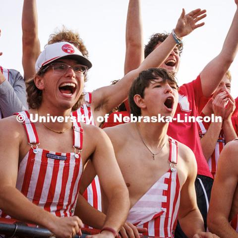 Fans wearing red and white striped overalls cheer at the Huskers vs. Wisconsin football game. November 23, 2024. Photo by Kristen Labadie / University Communication.