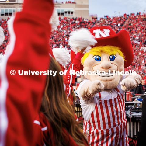 Herbie Husker wearing red and white striped overalls points at the camera at the Huskers vs. Wisconsin football game. November 23, 2024. Photo by Kristen Labadie / University Communication.