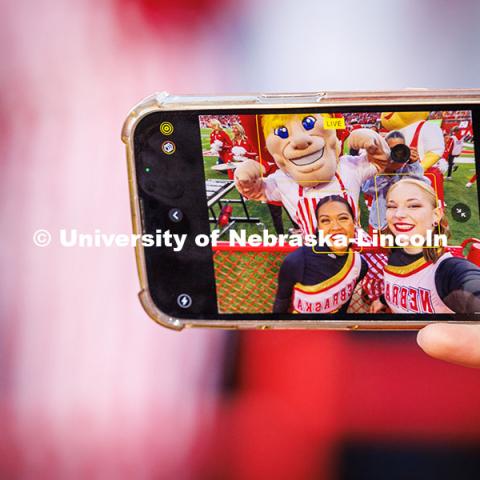 Nikki Duero (left) and Megan Timm, seniors on the UNL Color Guard, snap a selfie with Herbie Husker at the Huskers vs. Wisconsin football game. November 23, 2024. Photo by Kristen Labadie / University Communication.